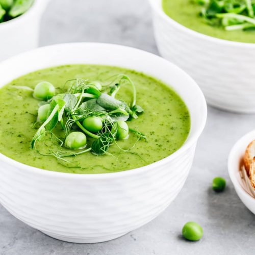Summer cream soup with green fresh pea shoots close-up